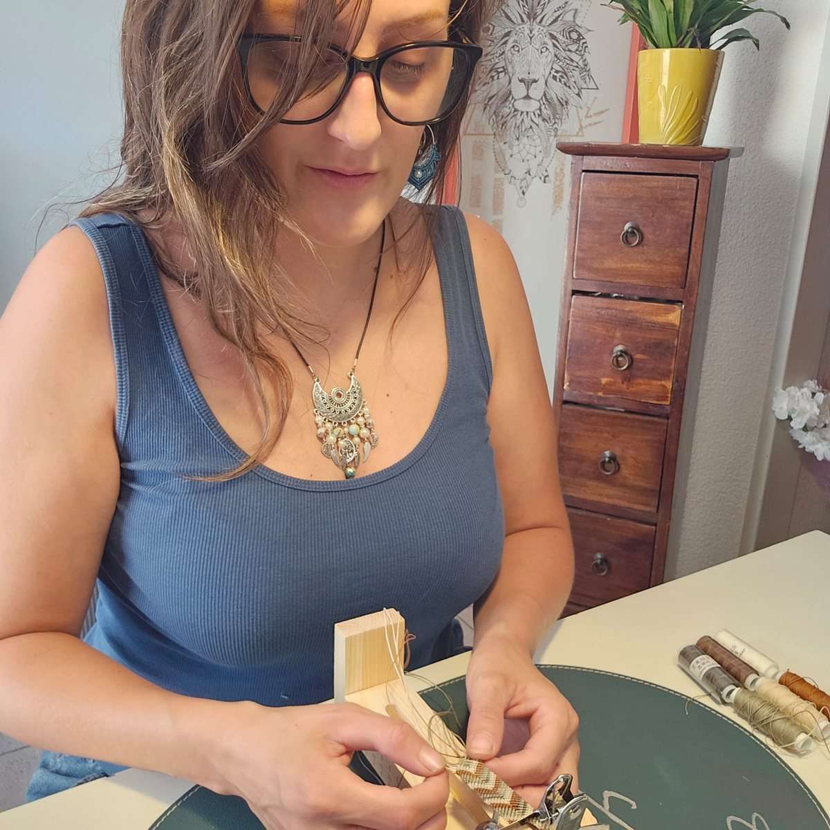 Harmony tisse un bracelet en macramé sur son métier de bois